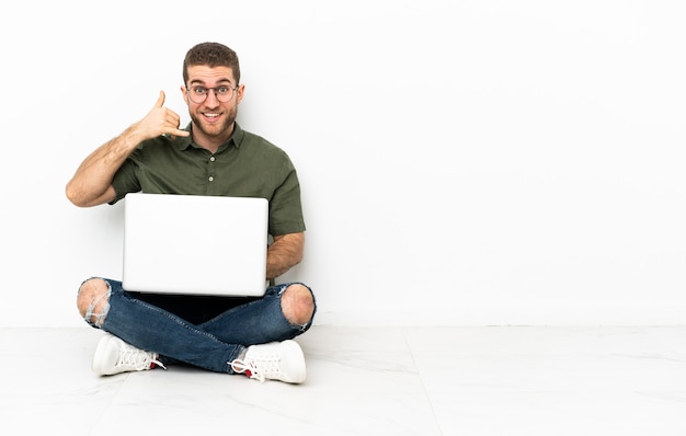 Homem sentado no chão com um laptop