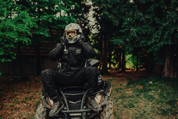 Homem sentado no quad na floresta e se preparando para passeio