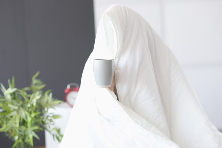 Foto homem sentado sob o cobertor com uma xícara de café. falta de conceito de sono