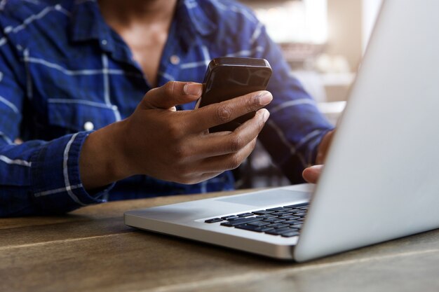 Homem, sentando dentro, segurando, telefone móvel, com, laptop