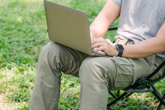 Homem, sentando, ligado, cadeira acampamento, e, trabalhando, com, computador laptop, jardim