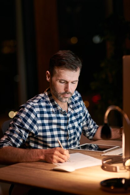 Foto homem sério assinando documentos à noite