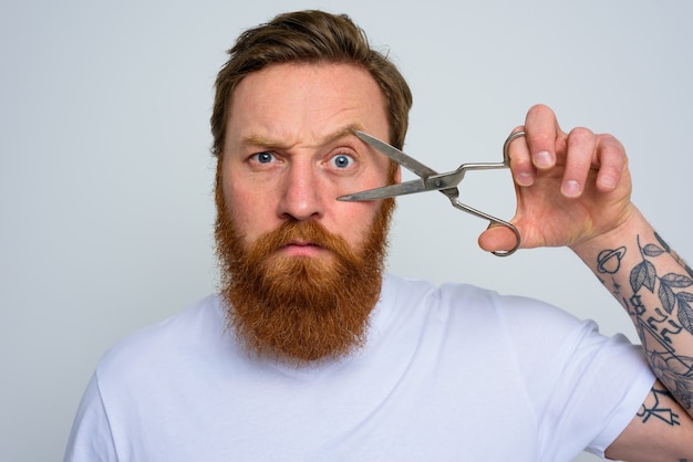 Homem sério com tesoura pronto para cortar a barba