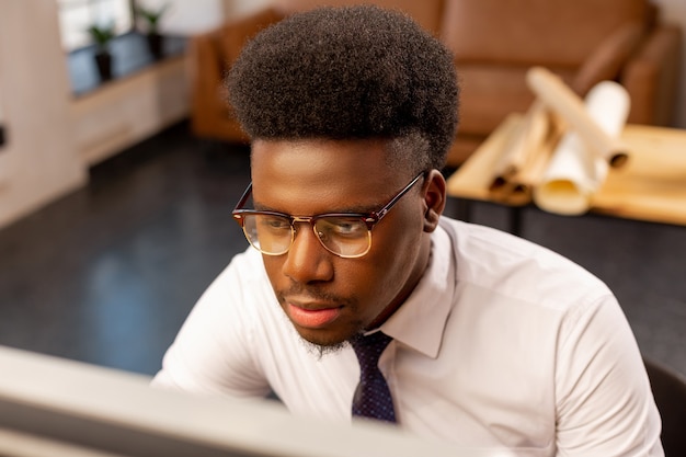 Homem sério digitando no computador enquanto trabalha no escritório