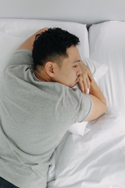 Homem sério e deprimido pensando demais nos problemas deitado na cama