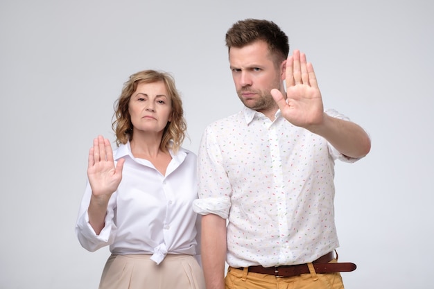 Homem sério e mulher fazendo o gesto de parada