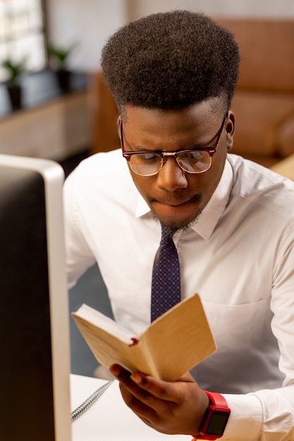 Homem sério e simpático estudando suas anotações enquanto planeja sua programação diária