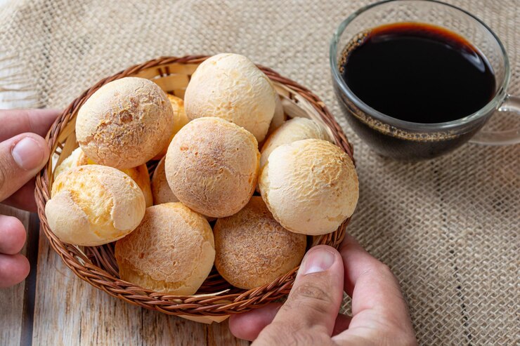 Foto homem serve pão de queijo na mesa de madeira conceito tradicional de refeição brasileira com comida típica