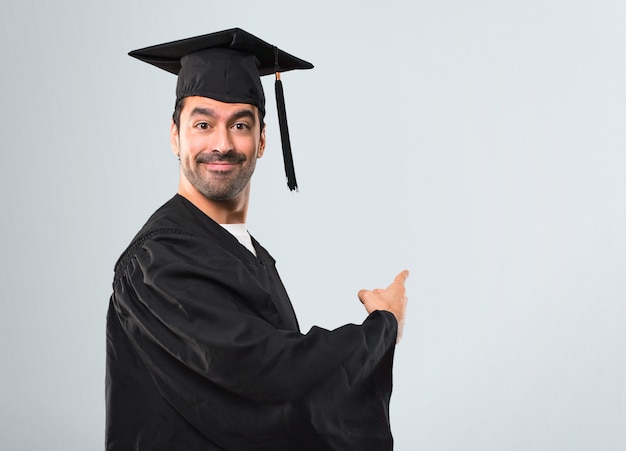 Homem, seu, dia graduação, universidade, apontar, costas, com, a, dedo indicador, apresentando