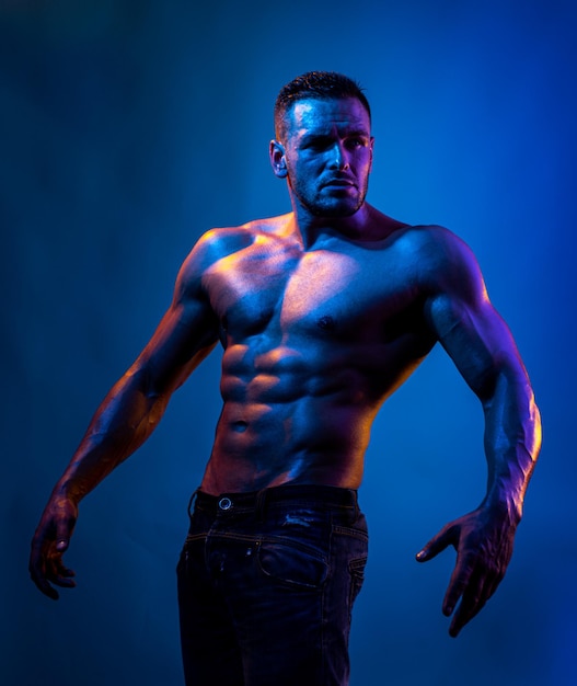 Homem sexy com corpo musculoso e torso nu. luz de néon azul.