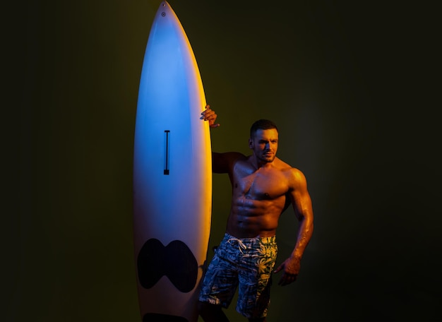Homem sexy de prancha de surf. Cara com placa de servo. Conceito de férias de verão. Surfista com prancha de surf. Retrato de atleta bonito com placa de servo. Lazer na praia masculina, férias de verão.