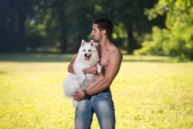 Homem sexy segurando cachorro Spitz alemão no parque