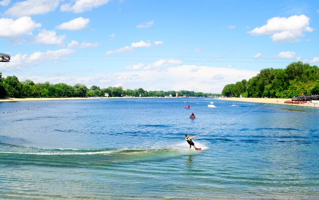 Homem skiinig no lago de água mantenha o cabo e faça uma grande onda