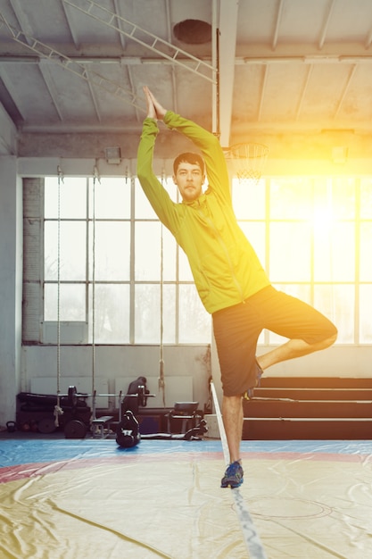 Homem slacklining andando e equilibrando em uma corda, slackline em um pavilhão desportivo