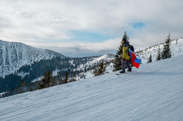 Homem snowboarder com bandeira da Eslováquia na encosta da estância de esqui