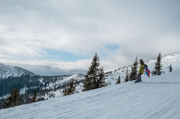 Homem snowboarder com bandeira da Eslováquia na encosta da estância de esqui