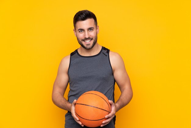 Homem sobre parede amarela isolada, jogando basquete