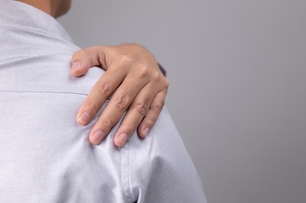 Homem sobrecarregado com uma torção no ombro e dores musculares. Depois de acordar, o homem tem um problema com seu corpo. Dor no ombro, dor escapular, síndrome do escritório e o conceito de ergonomia.