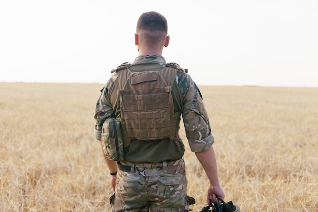 Homem soldado em pé contra um campo. Retrato de feliz soldado militar no campo de treinamento. Soldado do Exército dos EUA na Missão. guerra e conceito emocional.