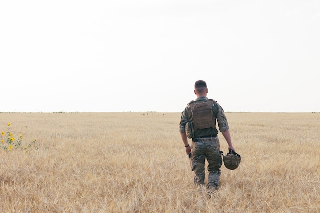 Homem soldado em pé contra um campo. Retrato de feliz soldado militar no campo de treinamento. Soldado do Exército dos EUA na Missão. guerra e conceito emocional.