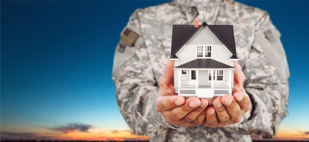 Homem soldado segurando um modelo da casa