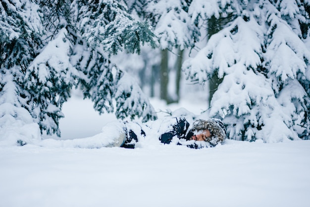 Homem solitário dormindo na floresta de neve