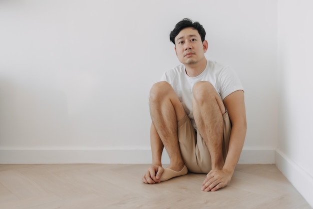 Foto homem solitário e deprimido sentado no canto da sala.