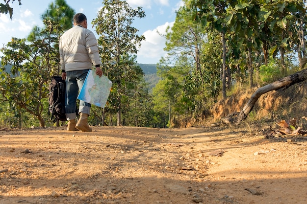 Homem solitário que usa jeans e botas de couro andando pelo caminho coberto de pedras.