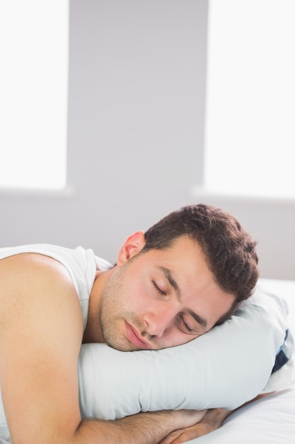 Homem sonolento e bonito relaxando na cama