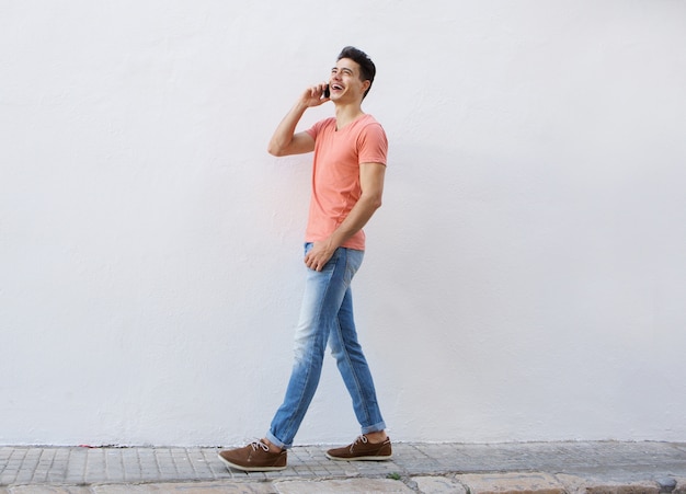 Homem sorridente andando e ouvindo o celular