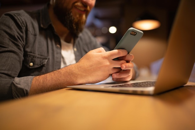 Homem sorridente barbudo navegando em smartphone