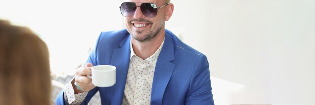 Homem sorridente bem vestido bebendo café em um café em reunião de negócios com o parceiro