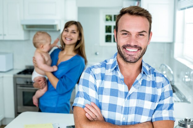 Homem sorridente com a família em segundo plano na cozinha