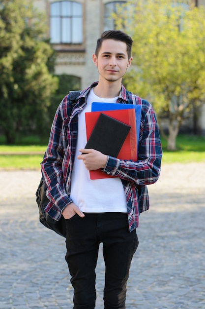 Homem sorridente com bolsa segurando notebooks campus