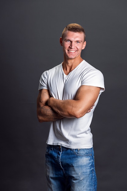 Homem sorridente com camiseta em branco na parede cinza