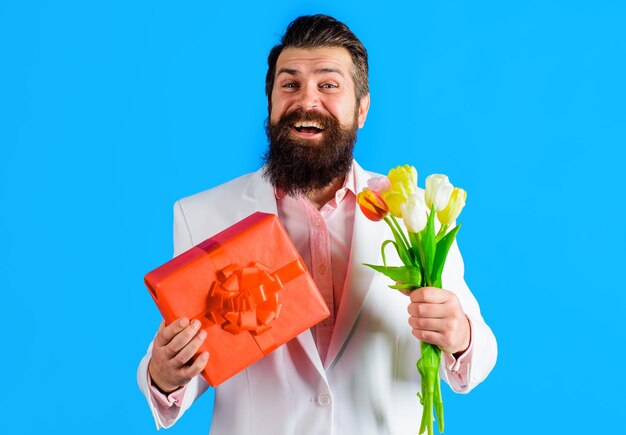 Homem sorridente com flores de tulipas de presente e buquê e presente para mulheres ou mães feliz aniversário