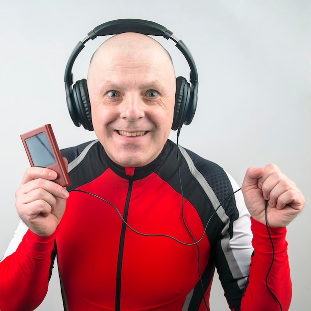 Homem sorridente com fones de ouvido e player digital portátil na mão relaxa enquanto ouve sua música favorita