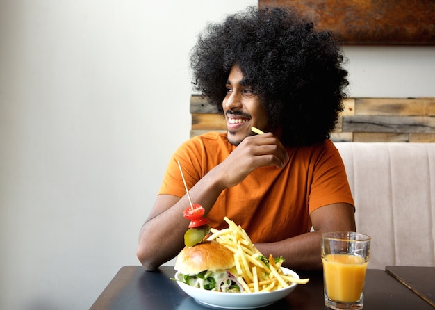 Homem sorridente, com, hamburger, e, frita, em, restaurante