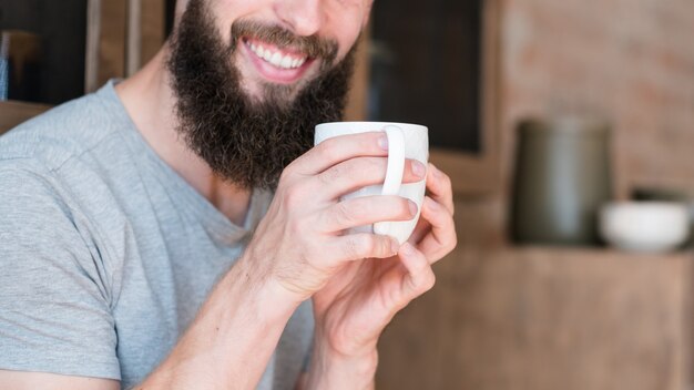 Homem sorridente com um copo de bebida quente. acorde e planeje a hora do dia.