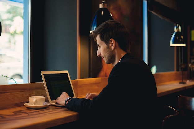 Homem sorridente, conversando no laptop tomando café