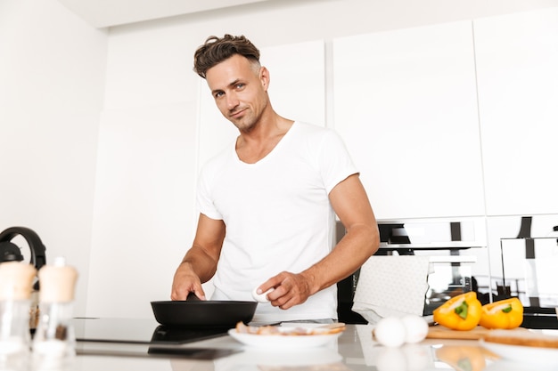 Homem sorridente cozinhando ovos para o café da manhã