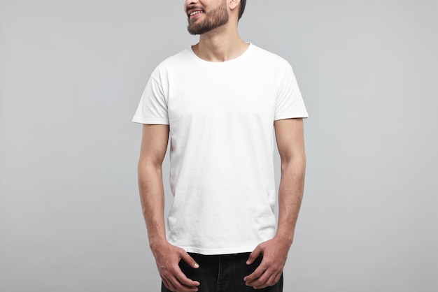 Homem sorridente de camisa branca em close de fundo cinza