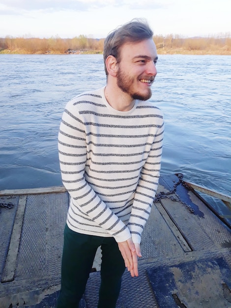 Homem sorridente de pé contra o lago
