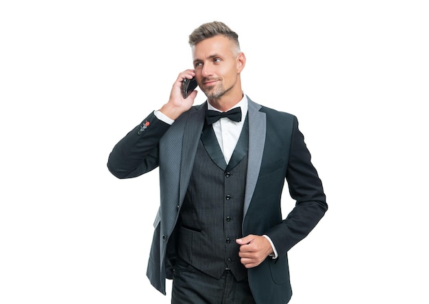 Homem sorridente de smoking falando no smartphone isolado no fundo branco