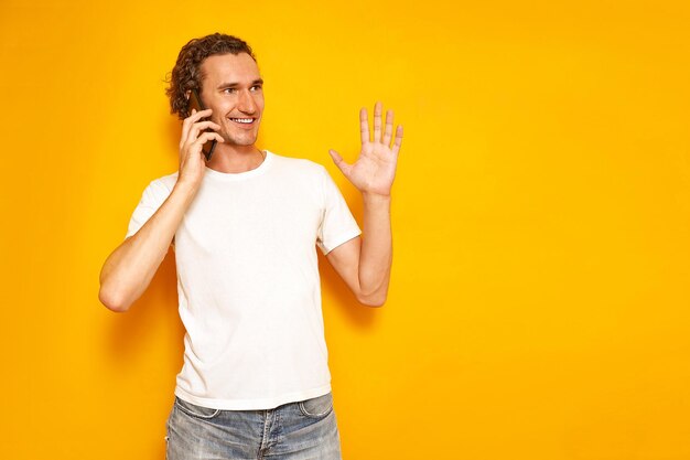 Homem sorridente está falando ao telefone gesticulando com a mão levantada, aproveitando o espaço de cópia de comunicação