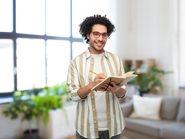 homem sorridente feliz com diário e lápis em casa