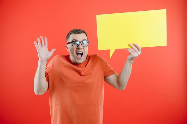 Homem sorridente feliz segurando o discurso de bolha amarela olhando para a câmera sobre fundo vermelho