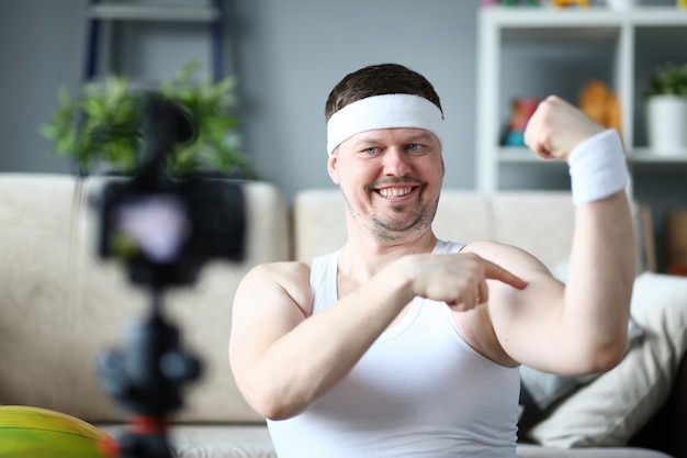 Homem sorridente, mostrando o bíceps e músculos nas mãos