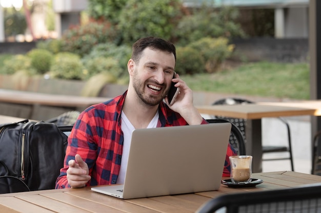 Homem sorridente navegando na net no laptop enquanto bebe café em um bar