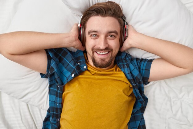 Homem sorridente ouvindo música na cama